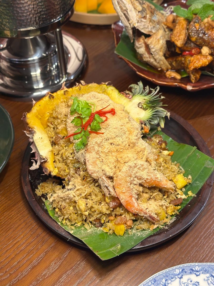 Fried rice served in a pineapple shell, topped with prawns, on a banana leaf at Pelangi
